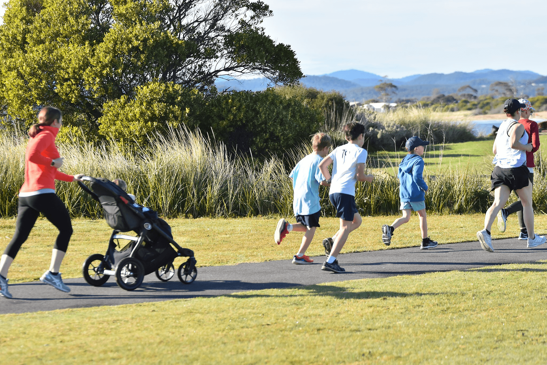 Children with adults pushing strollers running on path