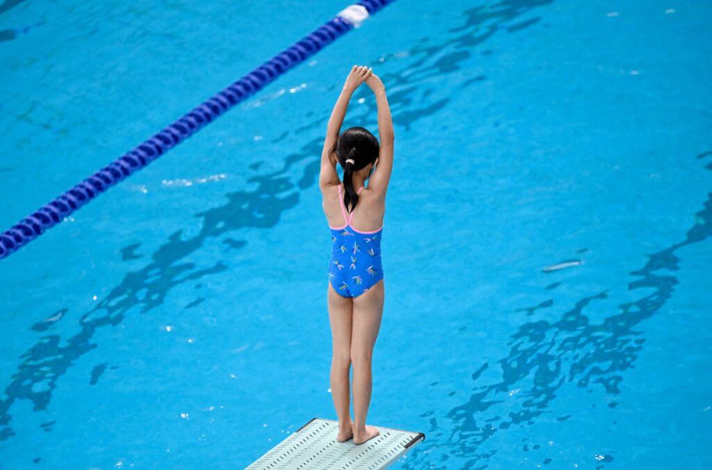 Girl preparing to diving off a diving board into an Olympic pool