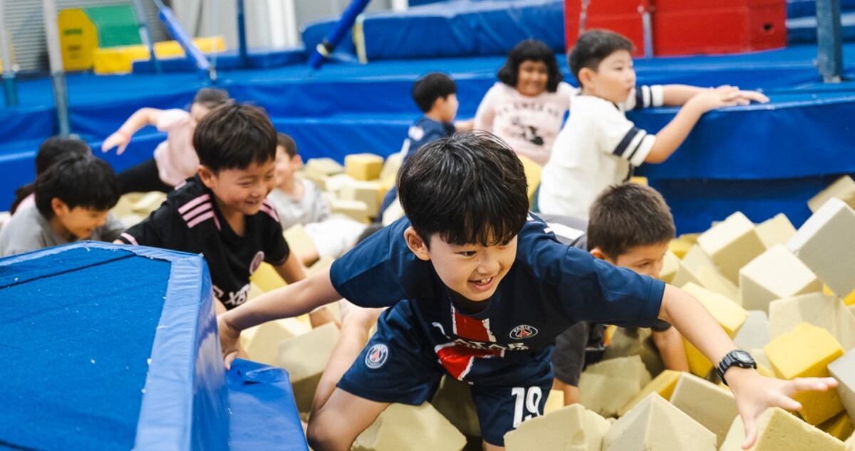 A group of children playing in a foam pit at an indoor gym.