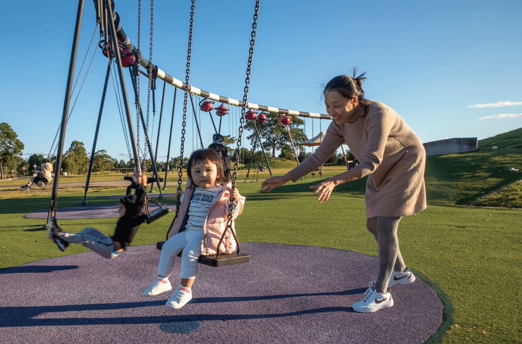 Blaxland Riverside Park playground adult with child on swing