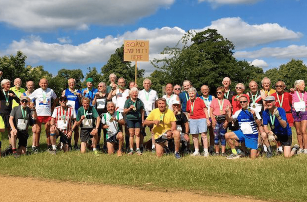 Many people gathering by a sign "80 and over meet here"
