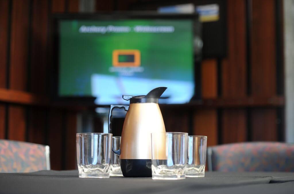 Image of kettle and cups in a boardroom facing a TV monitor