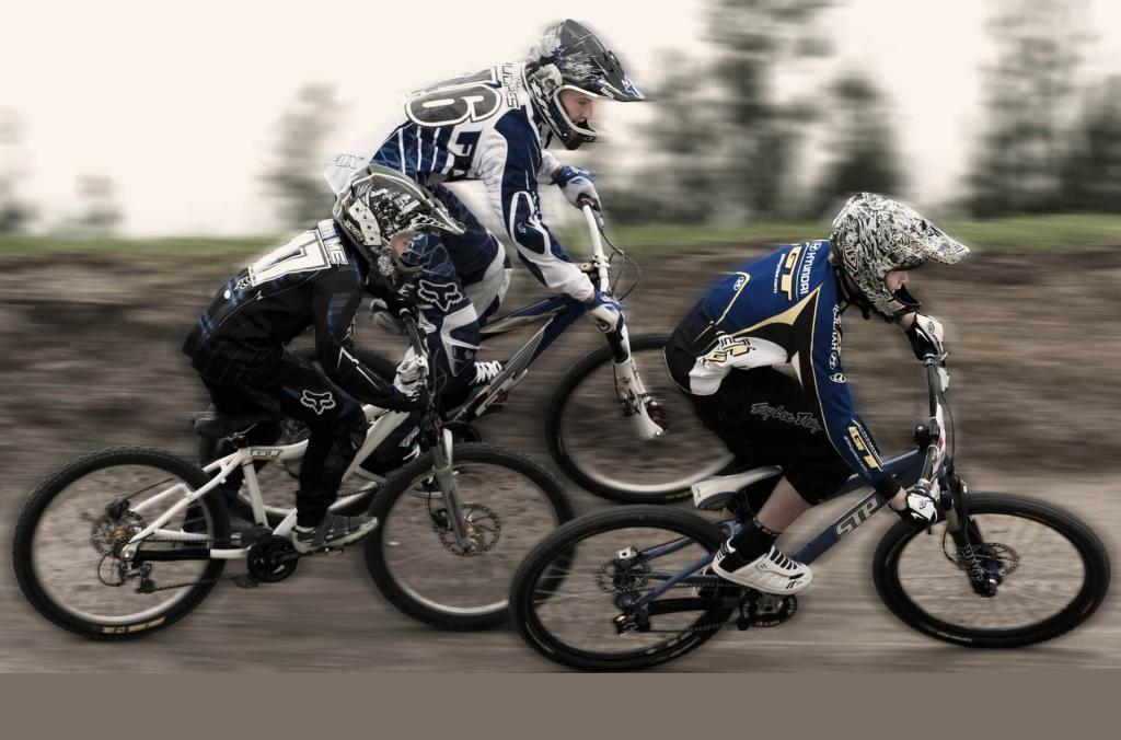 Three BMX riders on track bend racing