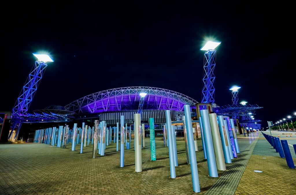 Olympic Boulevard light towers in blue, Games Memories artwork in foreground, Stadium Australia in background